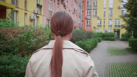 Camera is flying around. Back view of unrecognizable woman walks along the Stock Footage 171612319