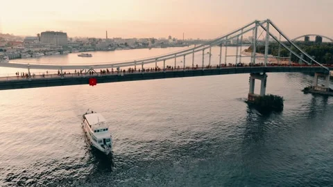 Camera flying away from a passing pleasure boat under a footbridge over a river Stock Footage 236391058