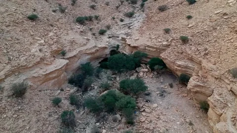 Camera flying over a canyon with a small natural Sha'ib Luha Pool Stock Footage 152699931