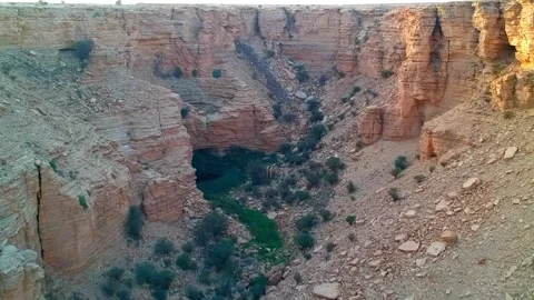 Camera flying over a canyon with a small natural Sha'ib Luha Pool Stock Footage 152700264