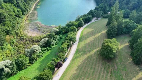 Camera flying over green valley approaching turquoise lake Video stock 285083986