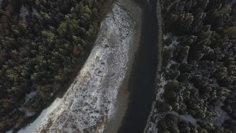 Camera flying over snowy forest and a river in mountains. Late afternoon.  Video stock 147632439