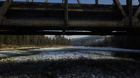 Camera flying under small steel bridge. Mountain river. Afternoon. Winter.  Stock Footage 147632122