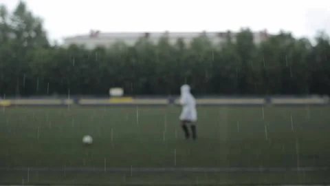 The camera focuses on the raindrops on the blurred background of the footballer 库存影片 135065983