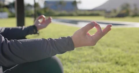 Camera is focusing on foreground hand while two are meditating with mudra on Stock Footage 347446323