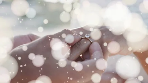 Camera focusing through bokeh, man placing diamond ring onto woman's finger, Stock Footage 337596445