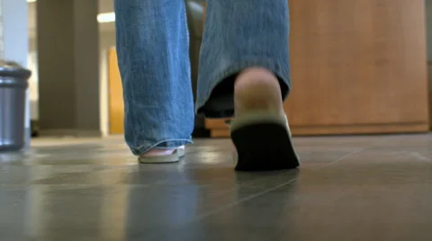 Camera following a man behind his feet walking through an office lobby Stock Footage 68246149