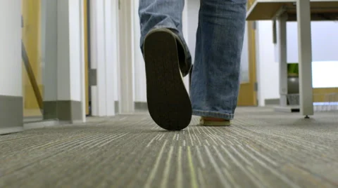 Camera following a man behind his feet walking through an office Stock Footage 68246639