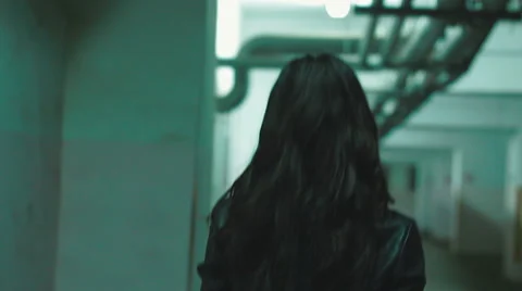 Camera following styled in leather clothes girl walking in the old garage Stock Footage 62656164