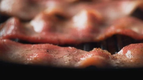 Camera follows adding dried herb on bacon cooked on grill. Slow Motion. Video stock 89886916