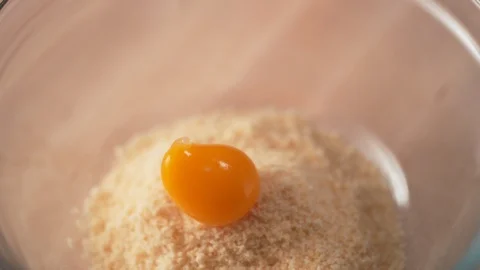 Camera follows adding egg into bread crumb in a bowl. Slow Motion. Stock Footage 104456458