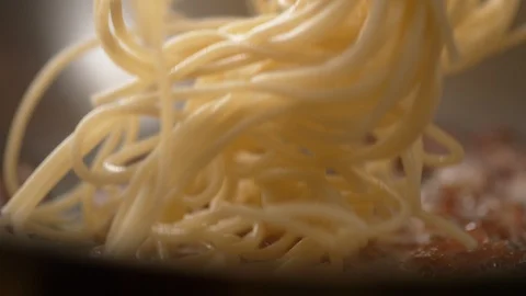 Camera follows adding spaghetti on cooked bacon. Slow Motion. Stock Footage 104458192