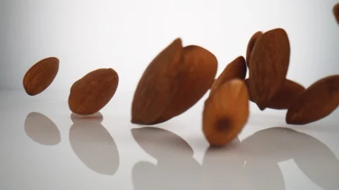 Camera follows almonds falling on surface. Slow Motion. Stock Footage 128768119