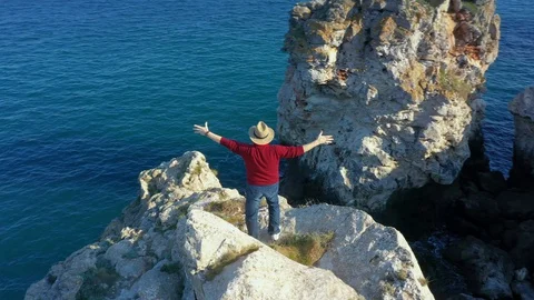 Camera follows around eldery man on top of rock in the sea.  Stock Footage 129599664