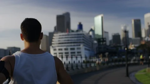Camera follows behind a young athletic male jogging, in slow motion Stock Footage 86843592