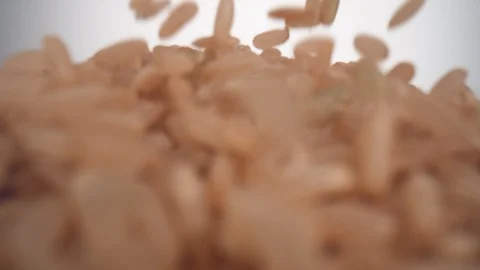Camera follows brown rice falling and making a heap on surface. Slow Motion. Stock Footage 128768594