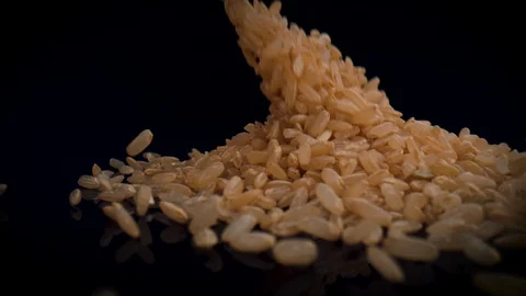 Camera follows brown rice falling on black surface. Slow Motion. Stock Footage 128769193