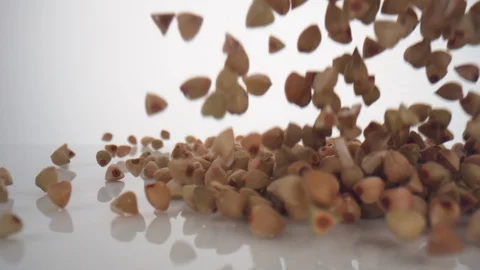 Camera follows buckwheat falling and making a heap on surface. Slow Motion. Stock Footage 128768708