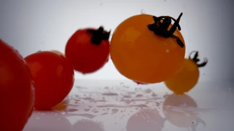 Camera follows cherry tomatoes falling on surface. Slow Motion. Stock Footage 128769670