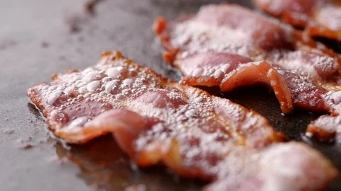Camera follows cooking bacon on grill. Bacon dolly in slow motion. Stock-Footage 128406424