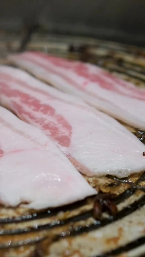 Camera follows cooking bacon on grill. Shot with high speed camera, phantom flex Stock Footage 306931664