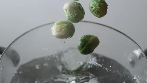 Camera follows cooking brussels sprouts in boiling water. Slow Motion. Stock Footage 98317119