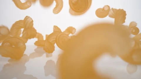 Camera follows dried macaroni pasta falling on surface. Slow Motion. Stock Footage 128767261