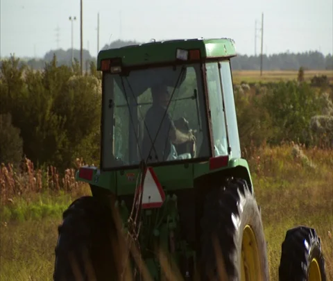 Camera follows grass-cutting tractor Stock Footage 86746901