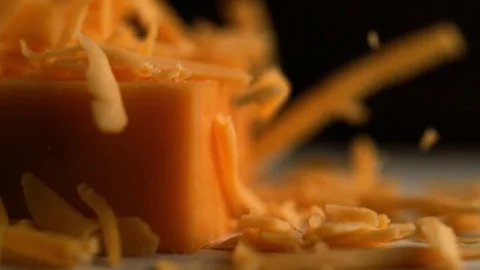 Camera follows grating cheddar cheese. Slow Motion. Stock Footage 84939236