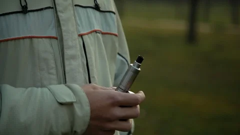 Camera follows hand of vaping boy in the park, close up Video stock 121061825