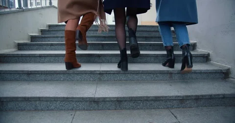 Camera follows legs of three beautiful happy business women in autumn coats Stock Footage 144211853
