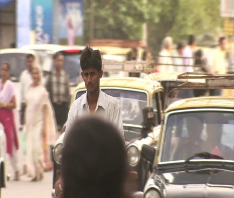 Camera follows man on bicycle moving through traffic with cars and taxis Stock Footage 86742787