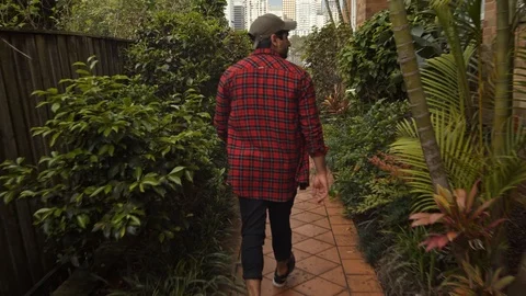 Camera Follows Man Walking Down Lush Garden Path Stock Footage 107898375