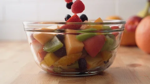 Camera follows putting fresh fruit into fruit salad. Slow Motion. Stock Footage 104461187