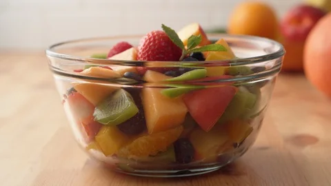 Camera follows putting fresh mint over fruit salad. Slow Motion. Stock Footage 104461083