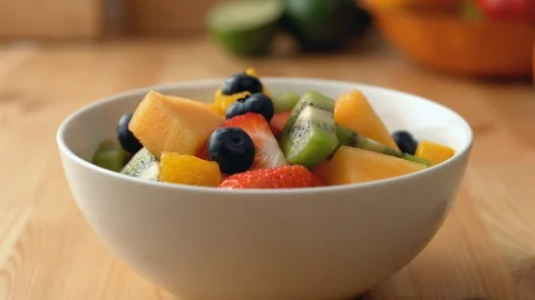 Camera follows putting mint leaves into a fruit salad bowl. Slow Motion. Stock Footage 121492183