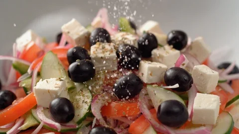 Camera follows putting salt over greek salad. Slow Motion. Stock Footage 104460880