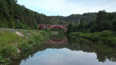 The camera follows the river, approaching the bridge. 스톡 동영상 112856104