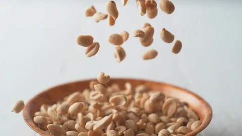 Camera follows salted peanuts falling into a bowl. Slow Motion. Stock Footage 89879191