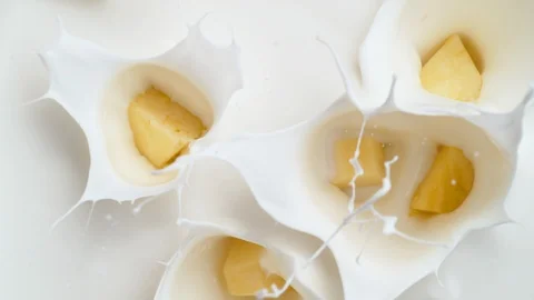 Camera follows tossing cut pineapple in milk. Overhead shot. Slow Motion. Stock Footage 94083869