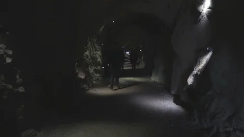 Camera footage people walking through the dark tunnel in the mountain Video stock 89619329