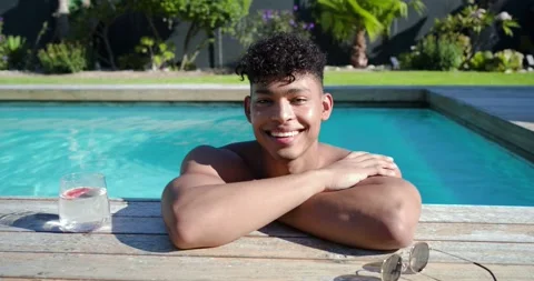 Camera gaze causing man keeping arms folded in pool, smiling with glass and Stock Footage 339415583