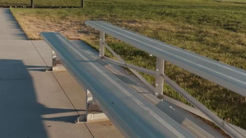 Camera Glides Over Empty Metal Bleacher Bench Beside a Sports Field Stockbeeldmateriaal 339136915