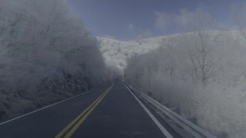 Camera glides up a two-lane mountain road through ice-covered trees Stock Footage 242347488