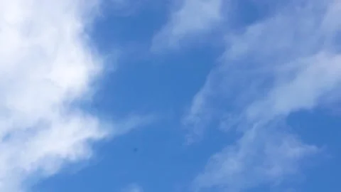 Camera glides upward to center of vivid blue sky with drifting clouds Stock Footage 312758217