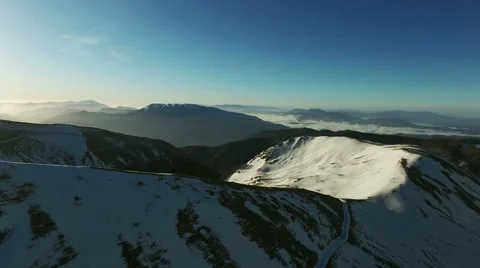 The camera goes over the snowy mountains. The camera goes down. Aerial  video. N Stock Footage 63472796