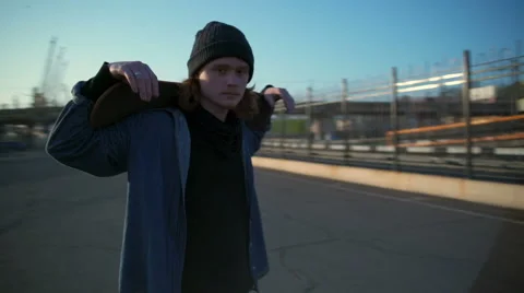 Camera goes round the young man holding a skateboard on shoulders slow motion Stock Footage 62399510