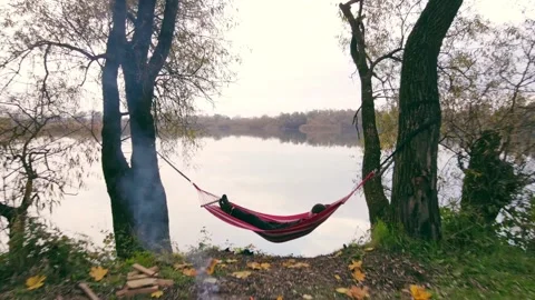 Camera going forward through tent woman laying on hammock autumn camping site Stock Footage 142451349