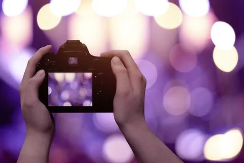 Camera in hands with free space for text. Live concert, crowd and lights in b Stock Photos