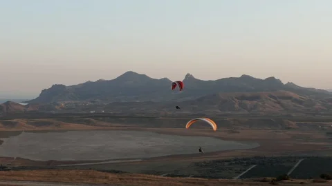 The camera harmoniously and smoothly follows the pilot with a parachute. The Stock Footage 120780018